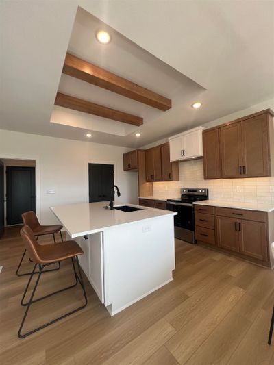 Kitchen with an island with sink, sink, light hardwood / wood-style flooring, stainless steel range with electric cooktop, and backsplash | Image 3