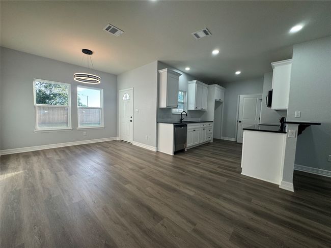 Kitchen featuring dark countertops, appliances with stainless steel finishes, dark wood-type flooring, white cabinetry, and recessed lighting | Image 6