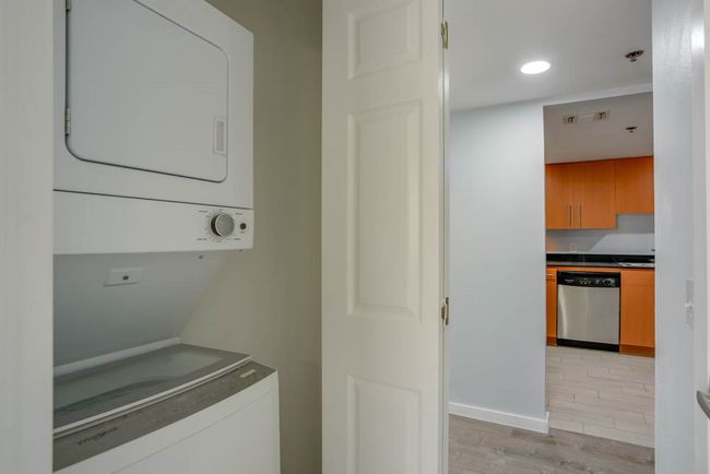 Laundry area featuring stacked washing machine and dryer and light wood finished floors | Image 14
