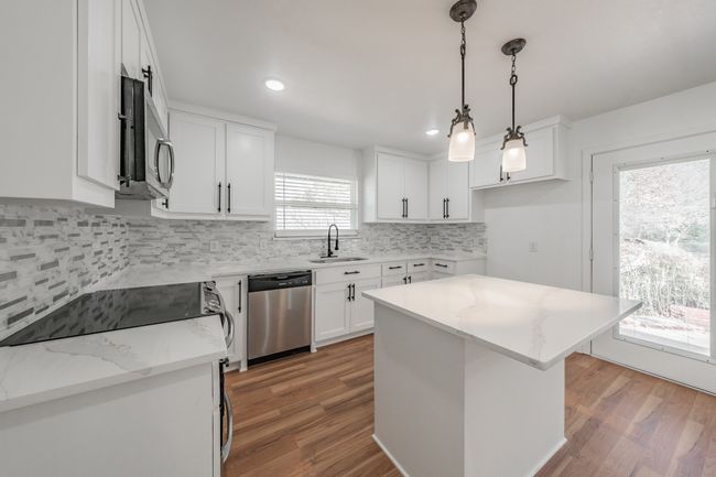 Kitchen with stainless steel appliances, a sink, light wood-style floors, white cabinets, and recessed lighting | Image 38