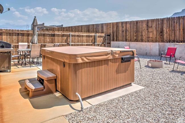 Fenced backyard with a hot tub, an outdoor fire pit, a patio, outdoor dining space, and grilling area | Image 20