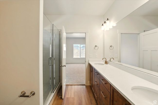 Bathroom with double vanity, a stall shower, and wood finished floors | Image 20
