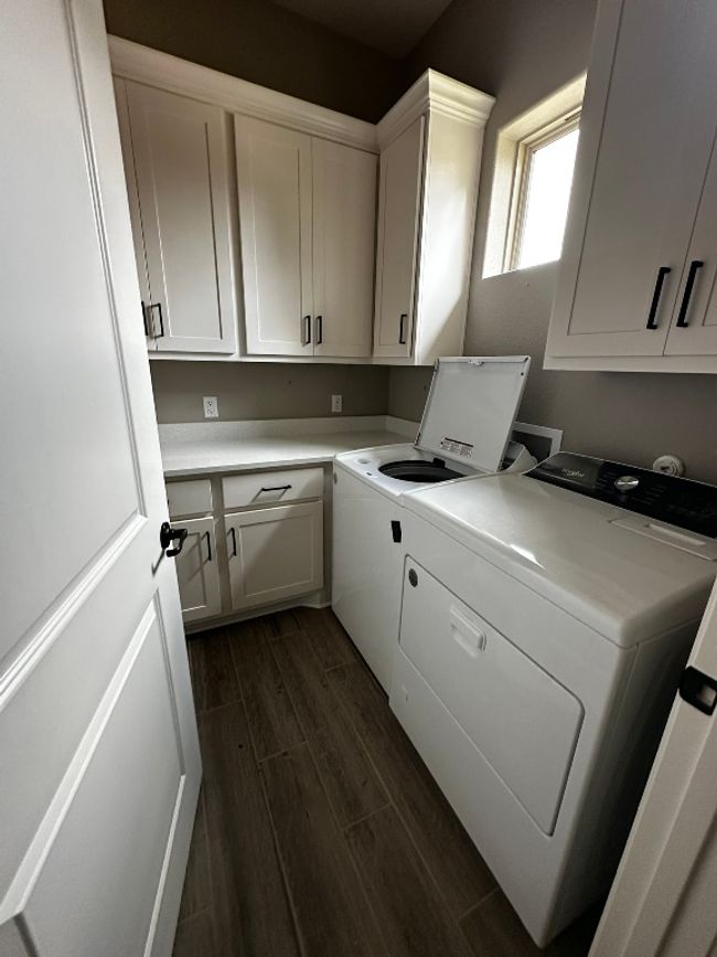 Laundry room featuring washer and clothes dryer, dark wood finished floors, and cabinet space | Image 15