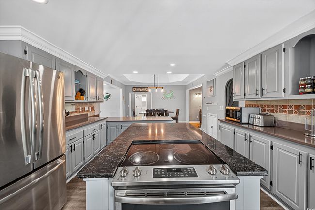 Kitchen featuring appliances with stainless steel finishes, gray cabinetry, a kitchen island, backsplash, and recessed lighting | Image 36