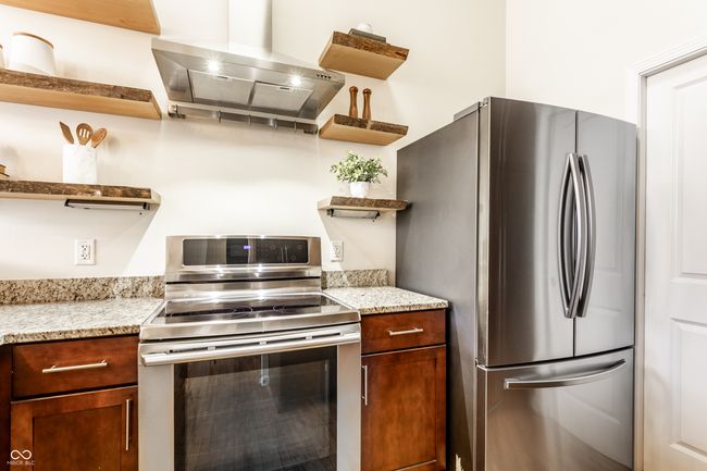 kitchen featuring open shelves, stainless steel appliances, extractor fan, and light stone counters | Image 16
