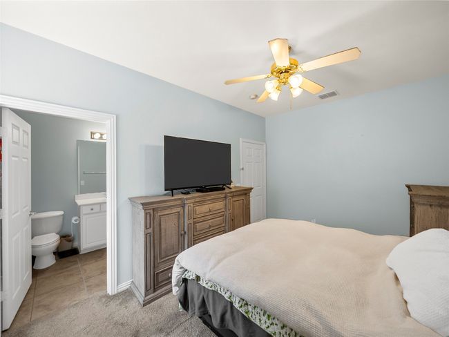 Bedroom with ceiling fan, ensuite bathroom, light carpet, visible vents, and baseboards | Image 24