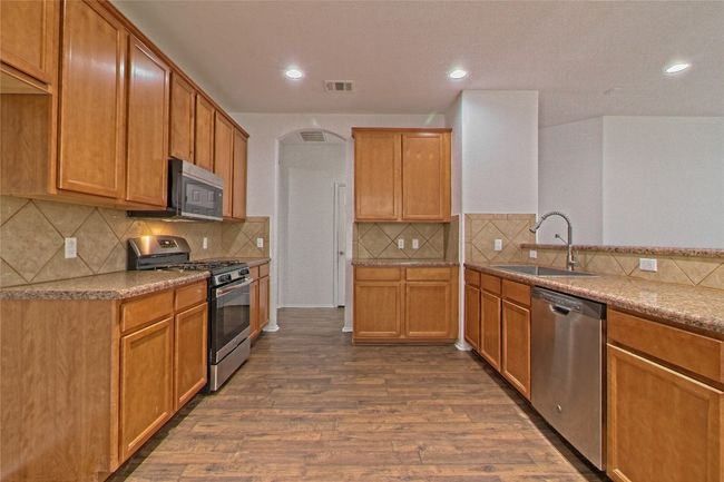 Kitchen with stainless steel appliances, dark wood-type flooring, tasteful backsplash, arched walkways, and recessed lighting | Image 13