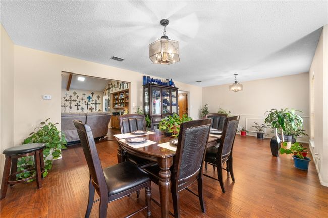 Dining area with dark hardwood / wood-style flooring, a notable chandelier, and a textured ceiling | Image 8