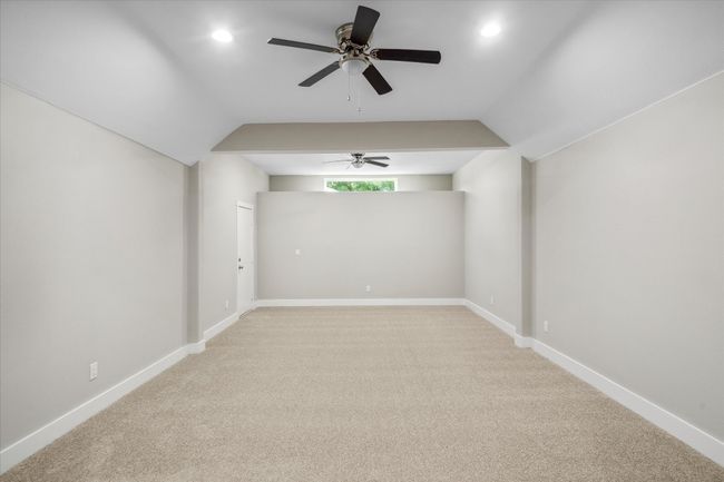 Empty room featuring vaulted ceiling, ceiling fan, light colored carpet, baseboards, and recessed lighting | Image 12