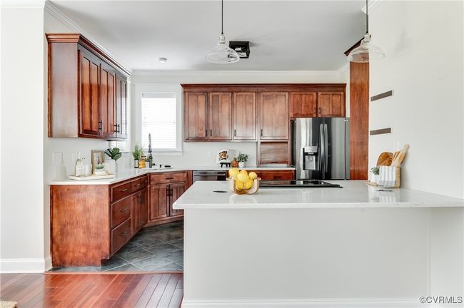 Kitchen featuring crown molding, a sink, appliances with stainless steel finishes, a peninsula, and dark wood finished floors | Image 15
