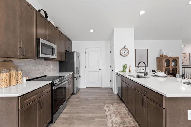 Kitchen with dark brown cabinets, sink, light hardwood / wood-style flooring, decorative backsplash, and appliances with stainless steel finishes | Image 19