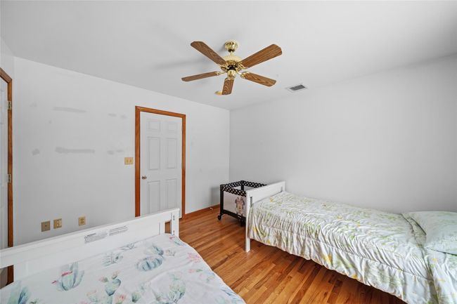 Bedroom with light wood finished floors, visible vents, and ceiling fan | Image 37