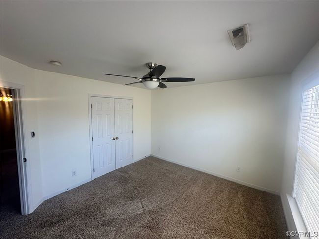 Unfurnished bedroom featuring ceiling fan, dark carpet, and a closet | Image 13