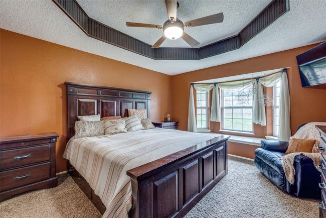 Bedroom featuring carpet flooring, a textured ceiling, a textured wall, a tray ceiling, and baseboards | Image 9