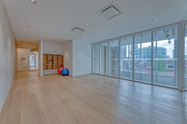 Workout room with light wood finished floors, visible vents, a view of city, a wall of windows, and recessed lighting | Image 21