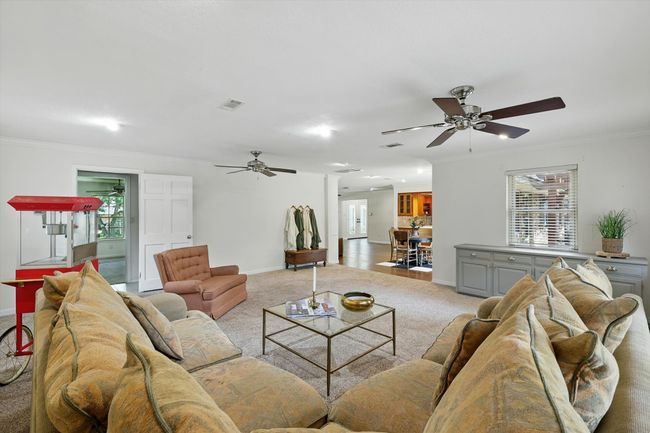 Carpeted living room featuring a ceiling fan and ornamental molding | Image 19