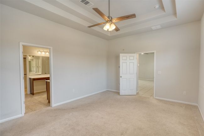 Unfurnished bedroom featuring a tray ceiling, light colored carpet, visible vents, and baseboards | Image 19