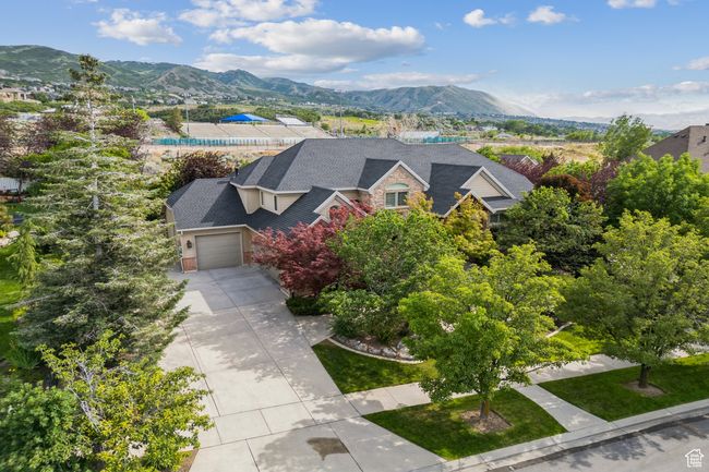 View of front of property featuring an attached garage, a mountain view, concrete driveway, and stone siding | Image 6