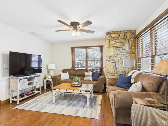 Living room featuring visible vents, baseboards, wood finished floors, and ceiling fan | Image 32