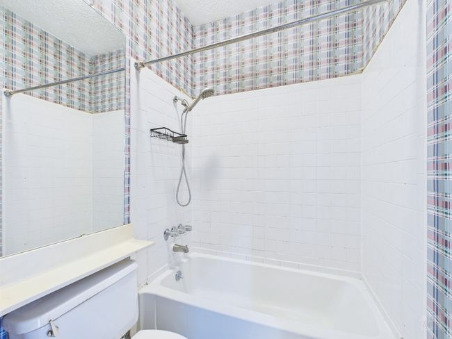 Full bathroom with wallpapered walls, shower / tub combo, and a textured ceiling | Image 32