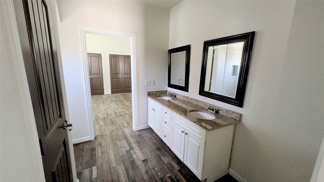 Full bath with double vanity, baseboards, a sink, and wood finished floors | Image 7