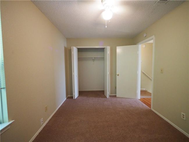 Unfurnished bedroom featuring carpet, a textured ceiling, a closet, baseboards, and a ceiling fan | Image 17
