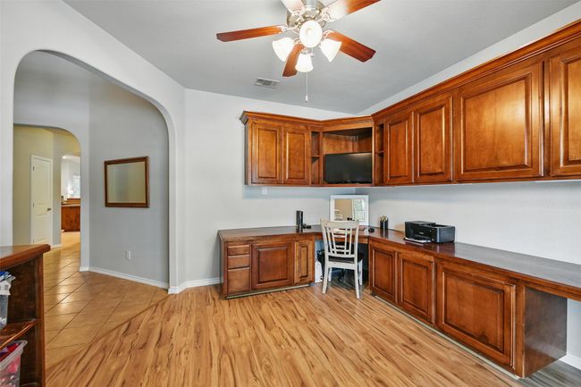 Office space featuring built in desk, arched walkways, and a ceiling fan | Image 13