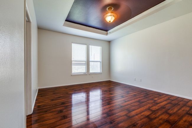 Spare room featuring baseboards, a tray ceiling, and hardwood / wood-style floors | Image 10
