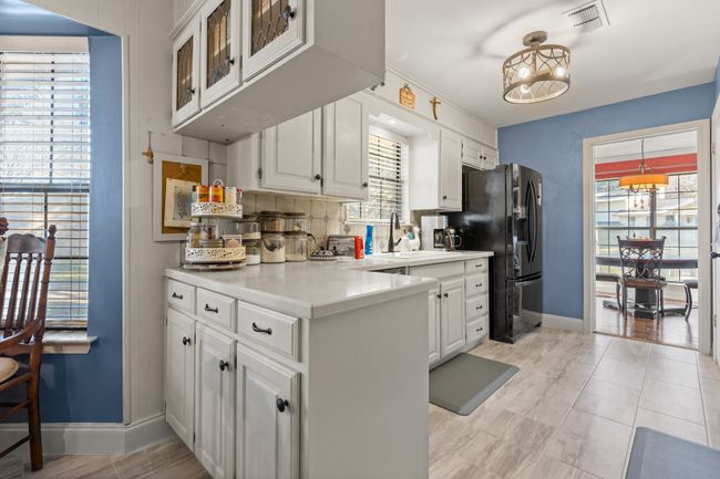 Kitchen featuring tasteful backsplash, white cabinetry, black refrigerator with ice dispenser, and sink | Image 15