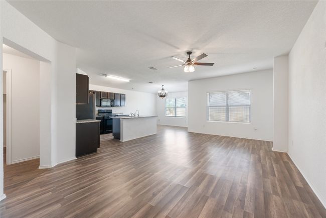 Unfurnished living room featuring a ceiling fan, dark wood-style flooring, and a chandelier | Image 4
