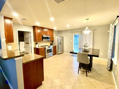 Kitchen with decorative light fixtures, light tile patterned flooring, granite-like formica countertops, appliances with stainless steel finishes, and kitchen peninsula | Image 3