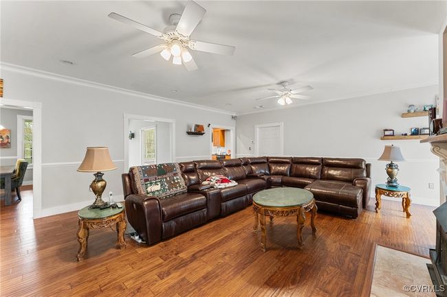 Living area featuring ceiling fan, wood finished floors, and ornamental molding | Image 7