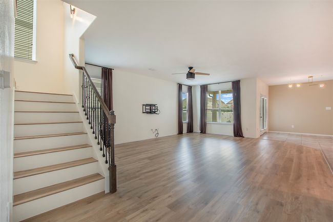 Unfurnished living room featuring light wood-type flooring, a ceiling fan, and stairs | Image 6