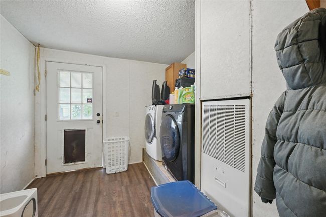 Laundry room featuring a heating unit, independent washer and dryer, wood finished floors, and a textured ceiling | Image 17