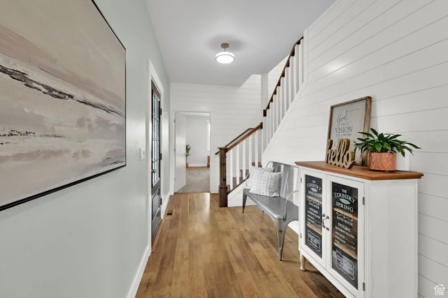 Foyer featuring stairway, wood finished floors, a dry bar, and wood walls | Image 21