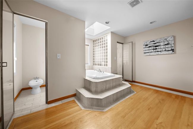 Bathroom with wood finished floors, visible vents, a garden tub, a skylight, and a bidet | Image 11