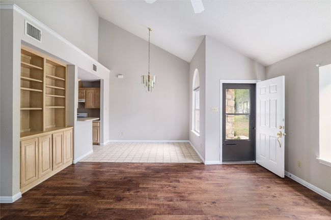 Entryway featuring wood finished floors, a chandelier, a ceiling fan, high vaulted ceiling, and baseboards | Image 7