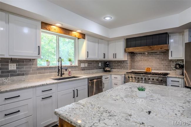 Kitchen featuring appliances with stainless steel finishes, white cabinetry, and decorative backsplash | Image 21