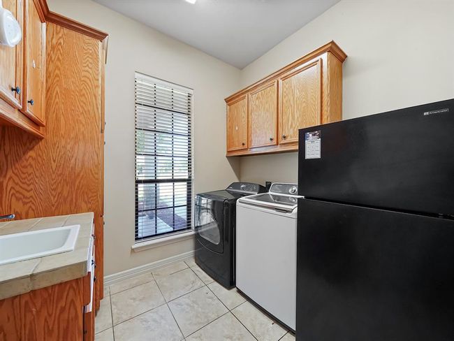 Spacious laundry room featuring ample cabinetry, modern appliances, and natural light from a large window, perfect for efficient and organized household chores. | Image 22