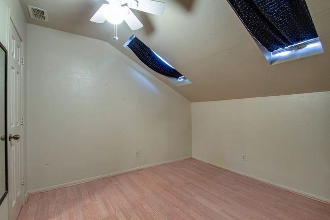 Additional living space featuring vaulted ceiling, light wood-style floors, ceiling fan, and a skylight | Image 20