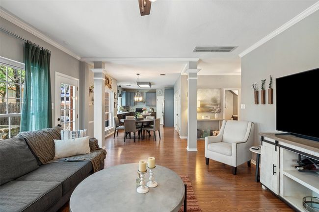 Living room with dark wood finished floors, decorative columns, visible vents, and ornamental molding | Image 19