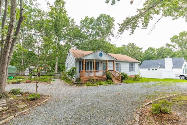 View of front of home with covered porch, driveway, view of wooded area, and a shingled roof | Image 6