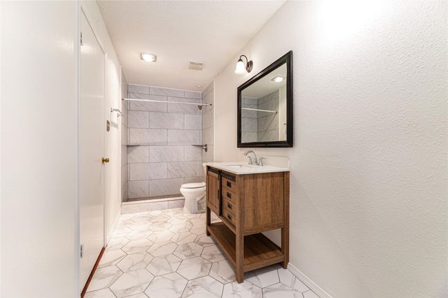 Bathroom with toilet, vanity, and a tile shower | Image 9
