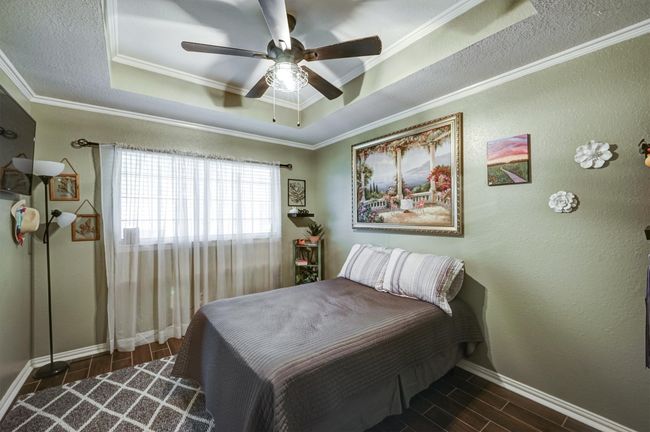 Bedroom featuring a raised ceiling, baseboards, ornamental molding, and wood tiled floor | Image 17