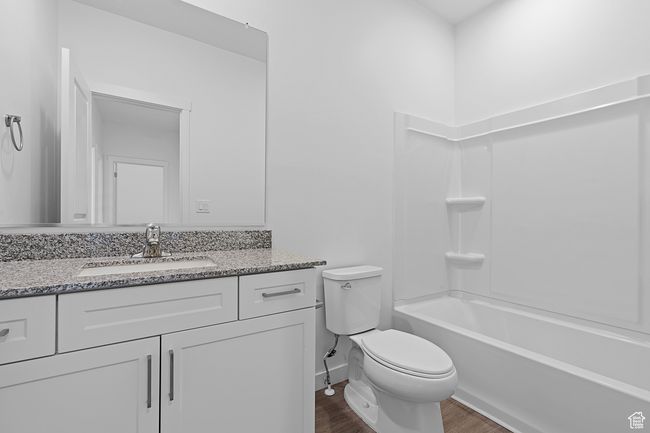 Bathroom featuring baseboards, toilet, bathtub / shower combination, vanity, and wood finished floors | Image 8