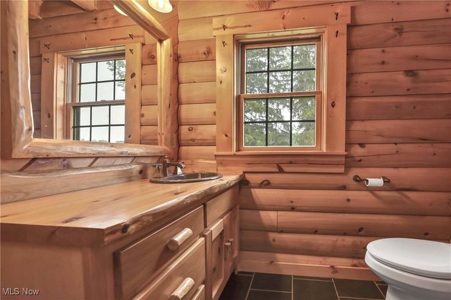 Wood vanity, wood framed mirror and toilet in first floor guest bath | Image 15