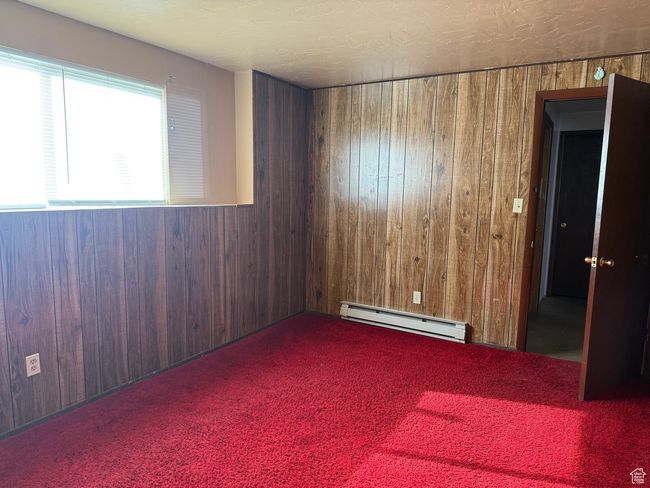 Carpeted spare room with a baseboard radiator and wooden walls | Image 26