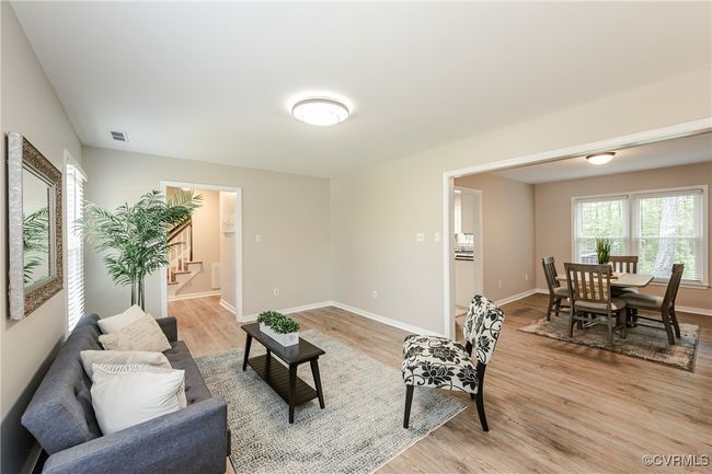 Living room featuring baseboards, visible vents, light wood finished floors, and stairs | Image 15
