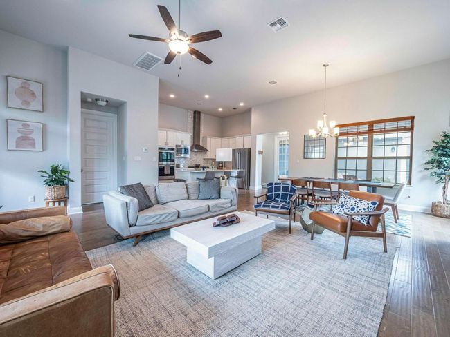 Living room with a chandelier, a ceiling fan, light wood-style floors, recessed lighting, and a high ceiling | Image 5
