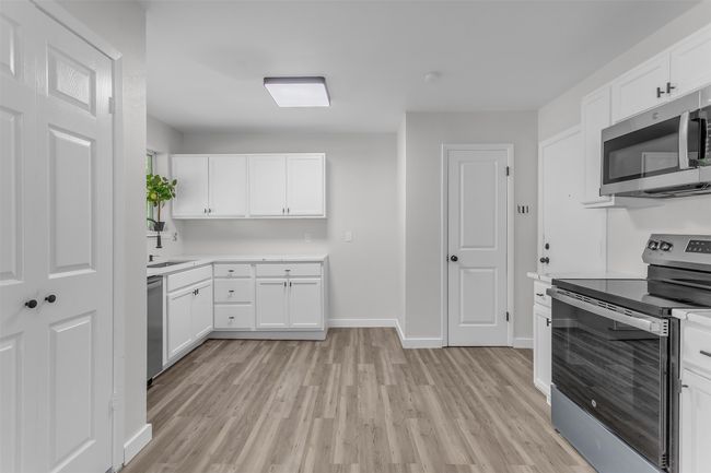 Kitchen with appliances with stainless steel finishes, light wood-style floors, light countertops, white cabinetry, and baseboards | Image 7